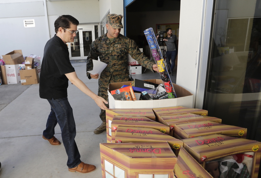Sgt. Christian Pastrana, right, and Matthew Williams prepare toys for a donation to the organization Women in Distress, at the Marine Corps Toys for Tots depot Wednesday in Hialeah, Fla.
