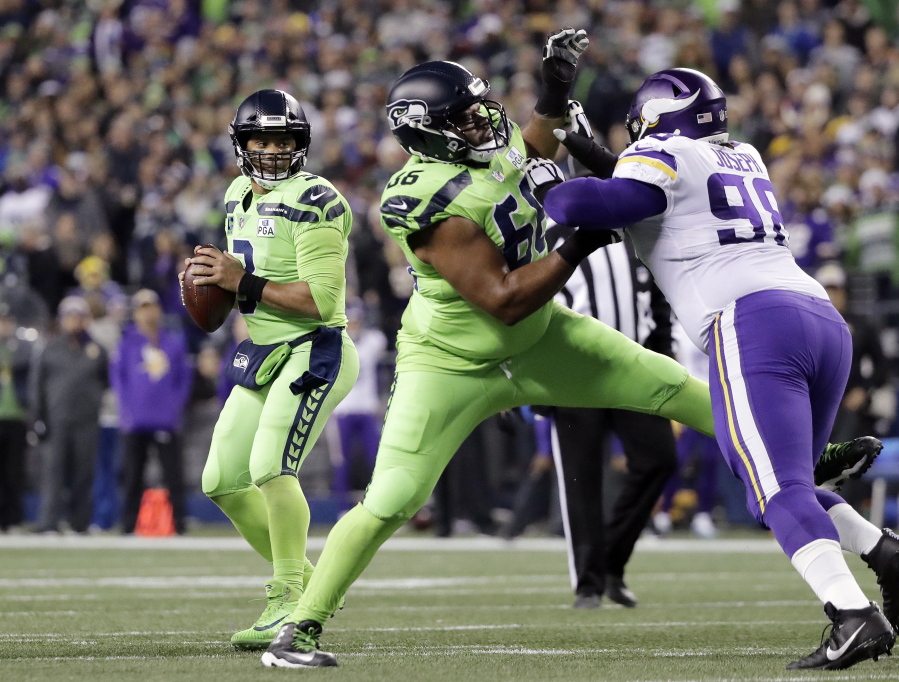 Seattle Seahawks quarterback Russell Wilson, left, looks for room to pass as Jordan Simmons (66) tries to hold back Minnesota Vikings’ Linval Joseph Minnesota Vikings in the first half of an NFL football game, Monday, Dec. 10, 2018, in Seattle. (AP Photo/ Ted S.