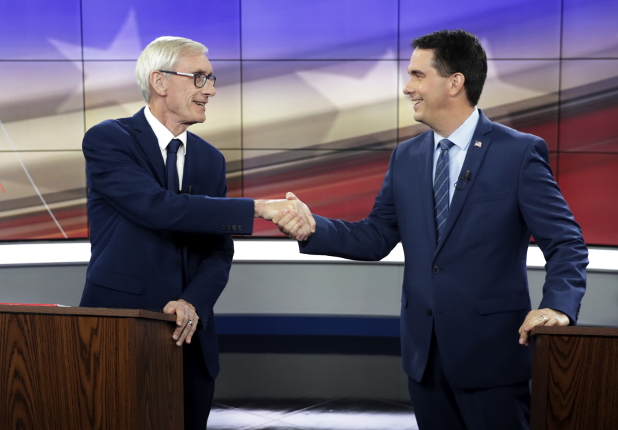 In this Oct. 19, 2018, file photo, Democratic challenger Tony Evers, left, and Wisconsin Gov. Scott Walker, a Republican, shake hands during gubernatorial debate in Madison, Wis. Republicans pushing to hang on to power in Wisconsin and Michigan aren’t stopping at curbing the authority of incoming Democratic governors. They’re also trying to hamstring Democrats who are about to take over as attorneys general.