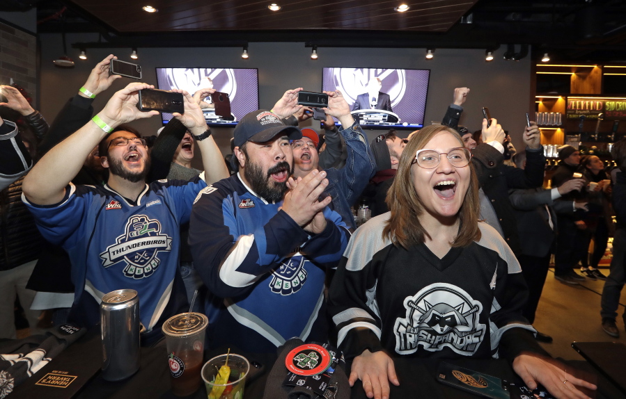 Ryan Kelly, from left, Otto Rogers and Rebecca Moloney cheer Dec. 4 the announcement of a new NHL hockey team in Seattle at a celebratory party in Seattle.