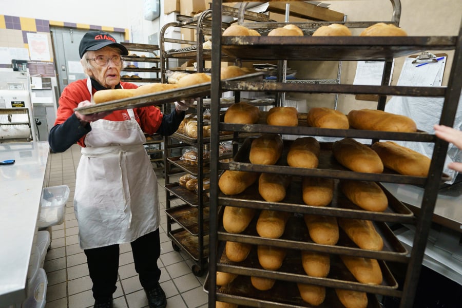 Giant bakery associate Wynnifred Franklin, 94, pulls freshly baked rolls from the bakery racks.