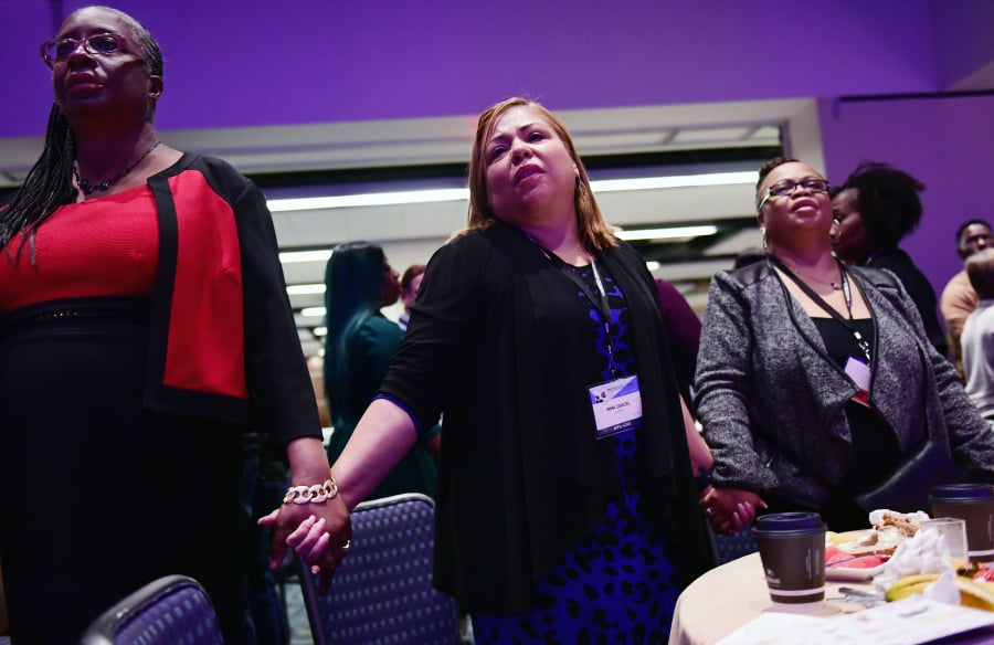 Velda Asbury, left, Irma Cancel and Chandra Best hold hands as the D.C. Labor Chorus performs at a prayer breakfast during the AFL-CIO Martin Luther King Jr. Civil and Human Rights Conference at the Washington Hilton on Sunday, Jan. 20, 2019. MUST CREDIT: Washington Post photo by Matt McClain.