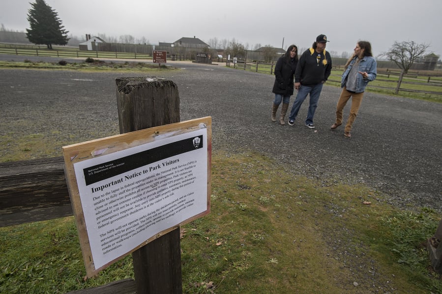 An informational message Monday morning at the Fort Vancouver National Historic Site informs visitors such as Angie and Enrique Perez of Arizona, from left, and longtime friend Andrew Filipczak of Vancouver, of the closure at the park because of the federal government shutdown. Site workers were among those furloughed Dec. 21.