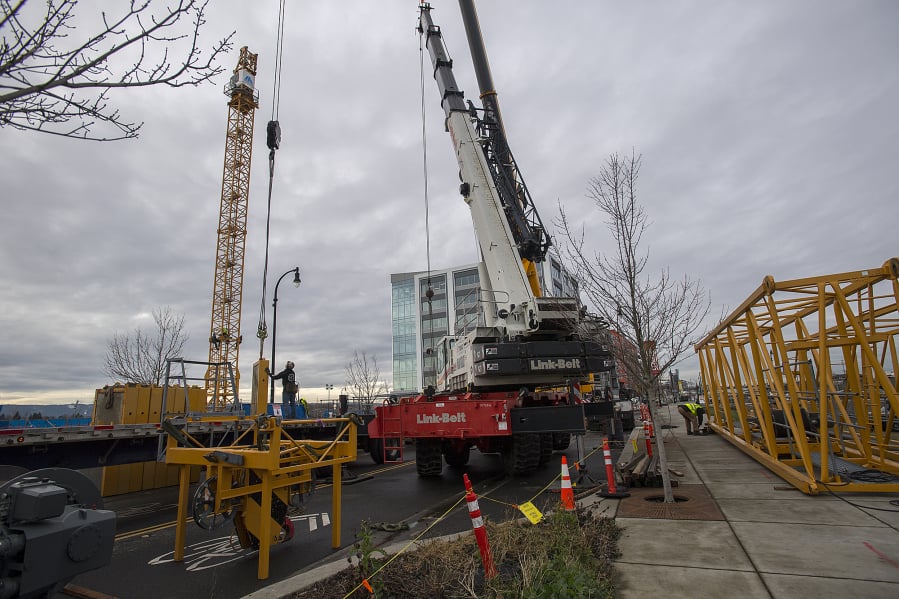 Construction workers unload pieces for assembly as they build the tower crane, left, that will be used to build the Hotel Indigo and Kirkland Tower at the Vancouver Waterfront.