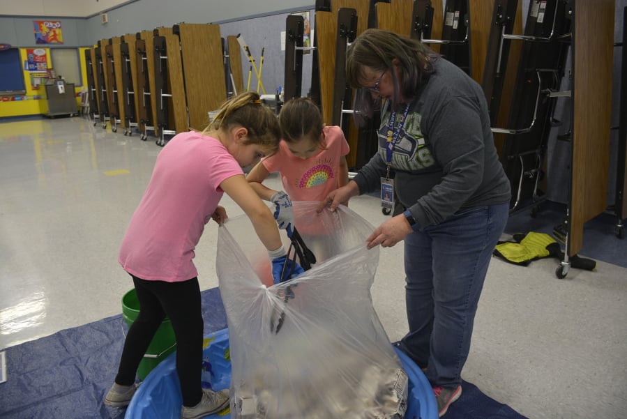 Washougal: Gause Elementary School students Parker Forsberg and Kamea Roy, from left, help Ellen Lancaster, Gause Day custodian and Green Team adviser, remove items mistakenly sorted in with milk cartons.