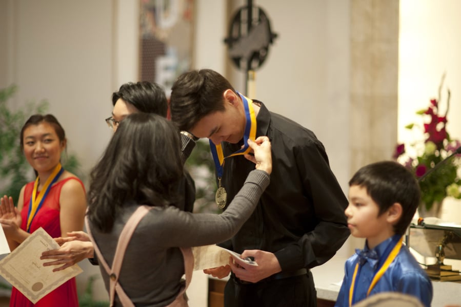 Union High School’s Aaron Greene, 17, and the other performers at the Vancouver Symphony Orchestra’s 25th annual Young Artists Competition get their medals Sunday at Trinity Lutheran Church after an afternoon of performing.