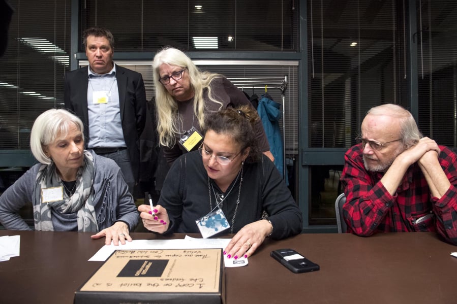 Liz Cline, from left in foreground, Katia Delavar and Jim Karlock tally votes for the top three nominees to fill the empty county council seat while witnesses watch during the Clark County Republican Party Central Committee’s meeting.
