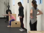 Richelle Endres, 10, of La Center, from left, squats during a Fit Kids class with instructor Kelsey Walsh and Aeryn Knowles, 11, of Vancouver, , at Salmon Creek Bridge Chiropractic. “I want to make them fall in love with what they’re doing,” Walsh said of her goal for the class.