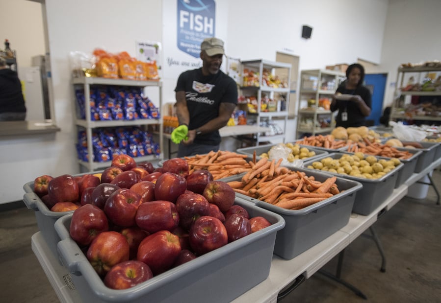 Volunteer Eddie Odoms, with hat, looks over the fresh fruit and vegetables available for those in need at FISH Westside Food Pantry of Vancouver on Monday morning.