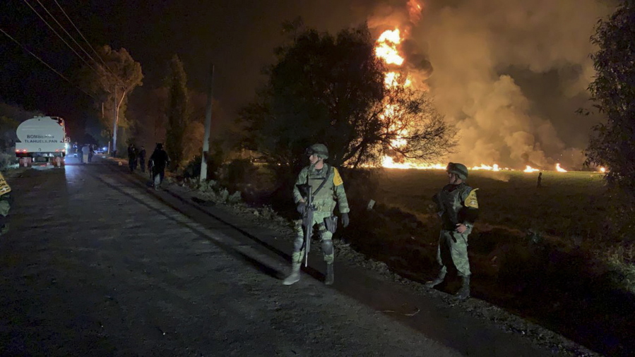 In this image provided by the Secretary of National Defense, soldiers guard in the area near an oil pipeline explosion in Tlahuelilpan, Hidalgo state, Mexico, Friday, Jan. 18, 2019. A huge fire exploded at a pipeline leaking fuel in central Mexico on Friday, killing at least 21 people and badly burning 71 others as locals were collecting the spilling gasoline in buckets and garbage cans, officials said. Officials said the leak was caused by an illegal tap that fuel thieves had drilled into the pipeline in a small town in the state of Hidalgo, about 62 miles (100 kilometers) north of Mexico City.