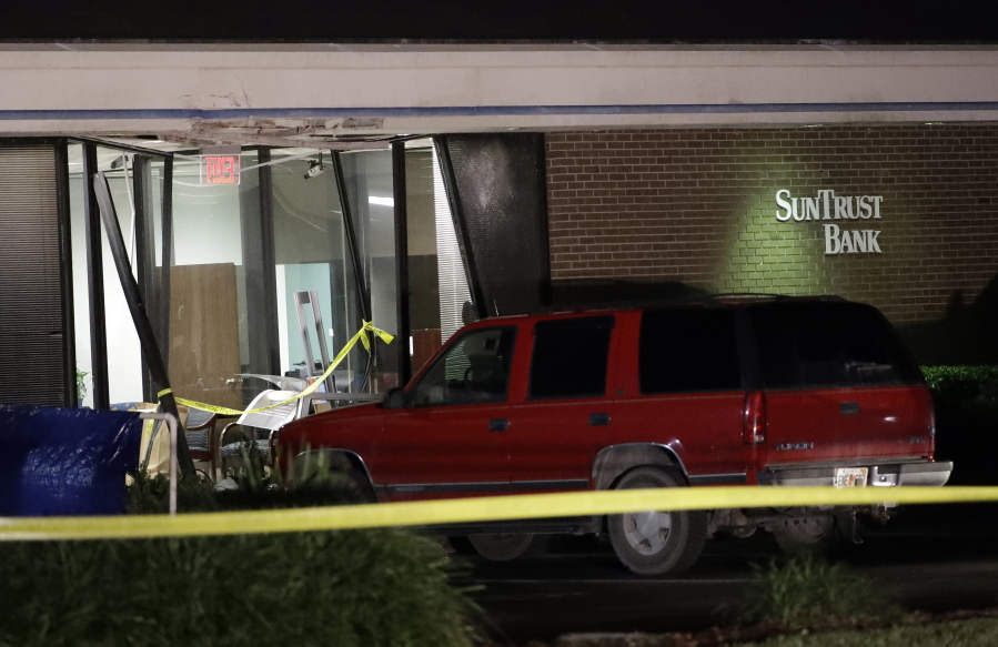 A red SUV is seen parked outside the damaged SunTrust bank early Thursday, Jan. 24, 2019, in Sebring, Fla. Authorities say five customers were shot and killed at the bank on Wednesday.