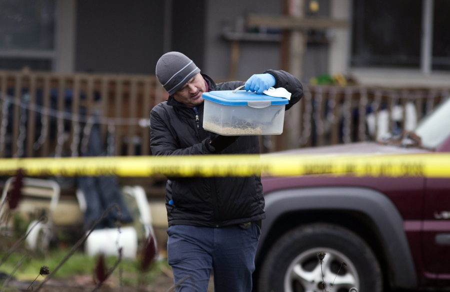 An investigator carries a box with a live snake, Monday, Jan. 21, 2019, outside a house where authorities say a man killed four members of his family, including his infant daughter, at the Canby, Oregon, home they shared, over the weekend.