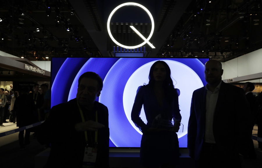 Attendees stand in front of a QLED TV at the Samsung booth during CES International in Las Vegas.