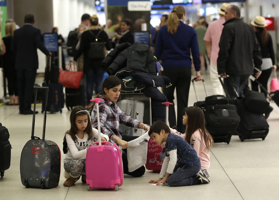 Travelers organize their luggage before entering a security checkpoint Friday at Miami International Airportin Miami. The three-day holiday weekend is likely to bring bigger airport crowds.