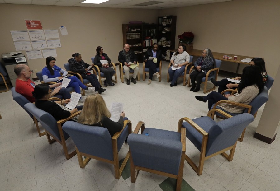 Annette Squetimkin-Anquoe, third from right, a member of the Colville Indian tribe and the Chief Traditional Health Officer at the Urban Indian Health Institute in Seattle, leads a talking circle meeting Friday, Jan. 11, 2019, to discuss the practice of traditional Indian medicine, including blessings and smudging, with employees of the Seattle Indian Health Board. Fallout from the federal government shutdown is hurting hundreds of Native American tribes and entities that serve them. The pain is especially deep in tribal communities with high rates of poverty and unemployment, and where one person often supports an extended family. (AP Photo/Ted S.