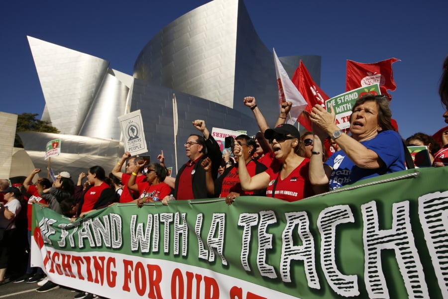 FILE - In this Dec. 15, 2018, file photo, United Teachers Los Angeles leaders are joined by thousands of teachers as they march past the Walt Disney Concert Hall downtown Los Angeles. The union representing striking teachers in Los Angeles says the strike will continue into its sixth school day on Tuesday, Jan. 22, 2019, regardless of the outcome of negotiations Monday.
