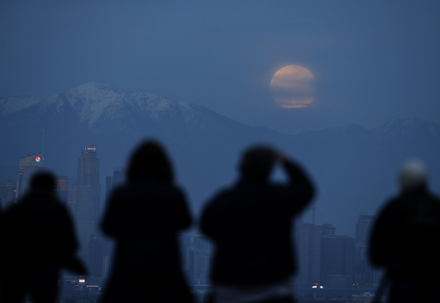 People watch the supermoon rise Sunday behind the downtown Los Angeles skyline, from Kenneth Hahn Park in Los Angeles. Ringo H.W.