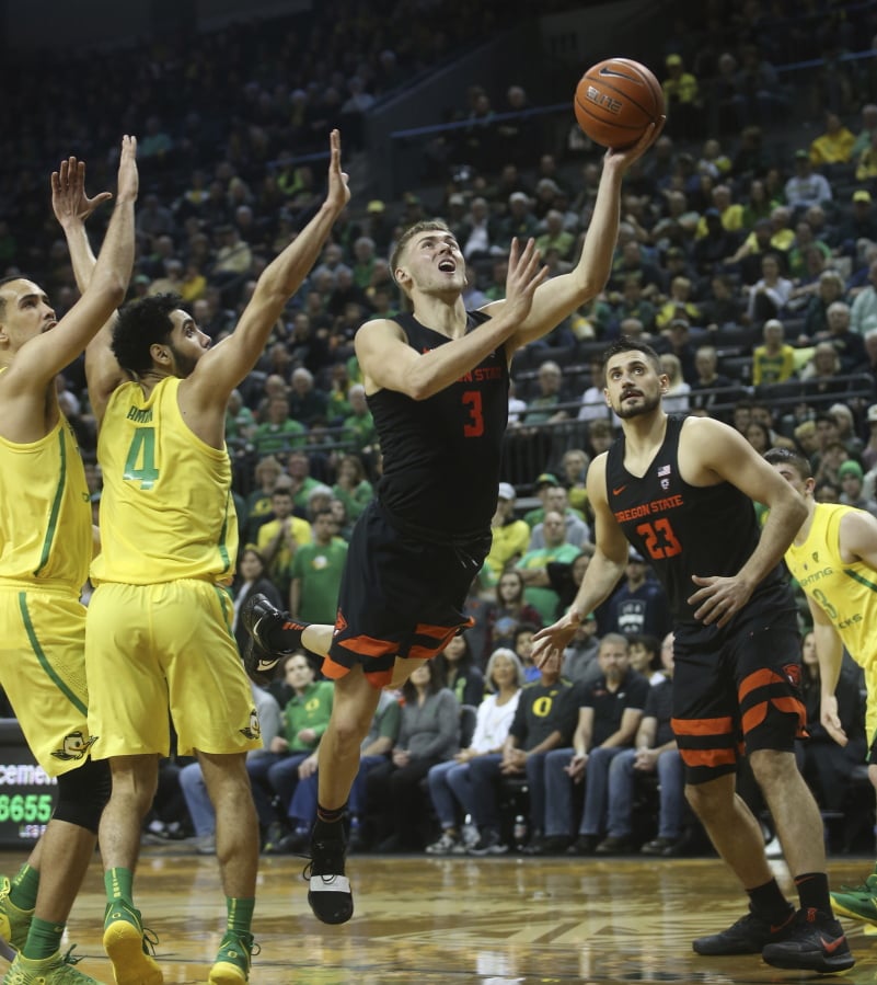 Oregon State’s Tres Tinkle, center, goes up to shoot between Oregon’s Paul White, left, Ehab Amin and teammate Gligorije Rakocevic, right, during the second half of an NCAA college basketball game Saturday, Jan. 5, 2019, in Eugene, Ore.