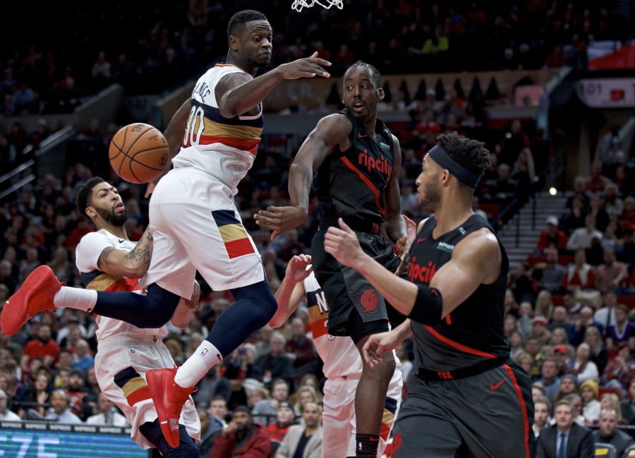 Portland Trail Blazers forward Al-Farouq Aminu, center, passes around New Orleans Pelicans forward Julius Randle during the second half of an NBA basketball game in Portland, Ore., Friday, Jan. 18, 2019. The Trail Blazers won 128-112.