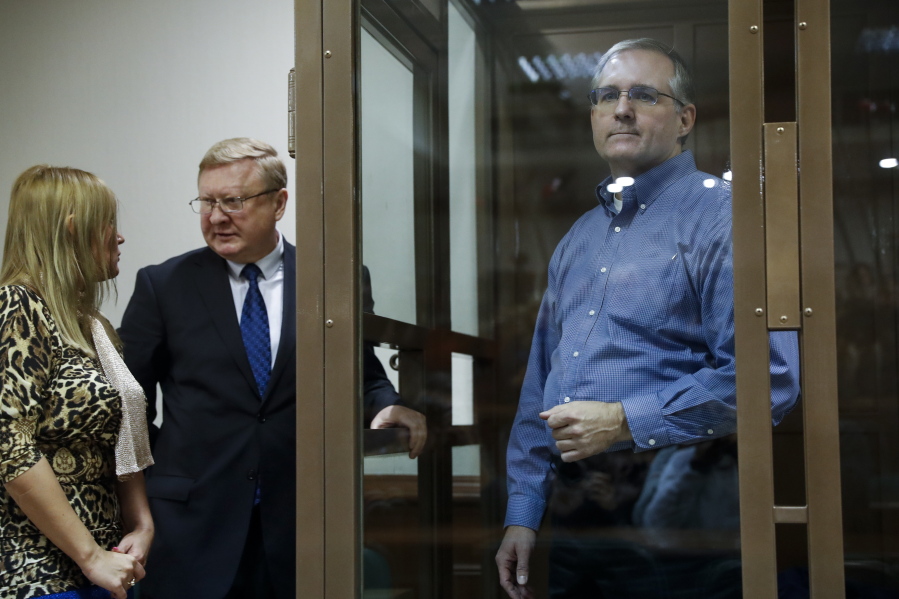 Paul Whelan, a former U.S. Marine, who was arrested in Moscow at the end of last year, right, looks through a cage’s glass as his lawyers talk to each other Tuesday in a court room in Moscow, Russia.