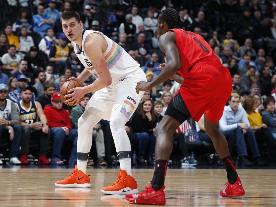 Denver Nuggets center Nikola Jokic, left, looks to pass the ball as Portland Trail Blazers forward Al-Farouq Aminu defends in the first half of an NBA basketball game Sunday, Jan. 13, 2019, in Denver.