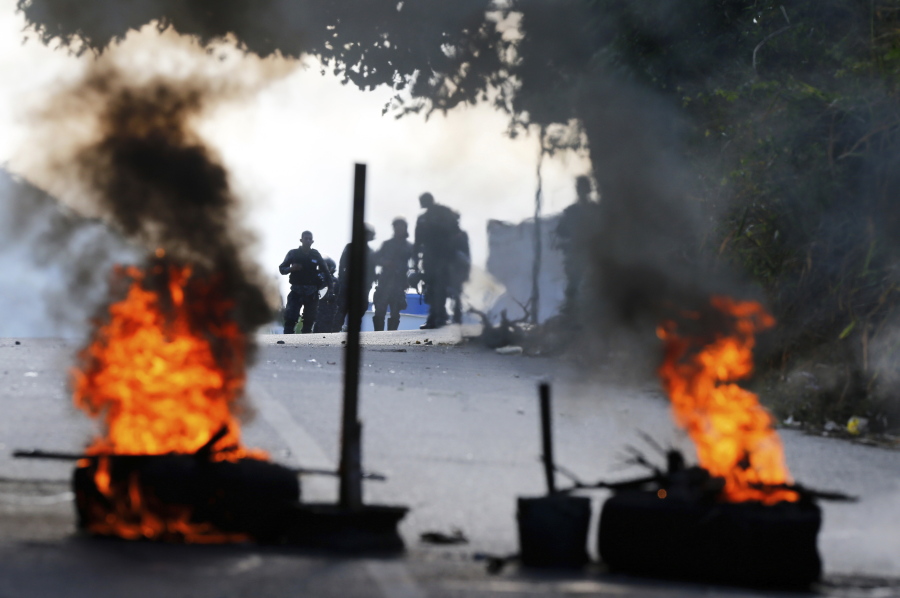 Bolivarian National Police stand behind a burning roadblock set up by anti-government protesters who are showing support for a mutiny by some National Guard soldiers in the Cotiza neighborhood of Caracas, Venezuela, Monday, Jan. 21, 2019. Venezuela’s government said Monday it put down the mutiny.