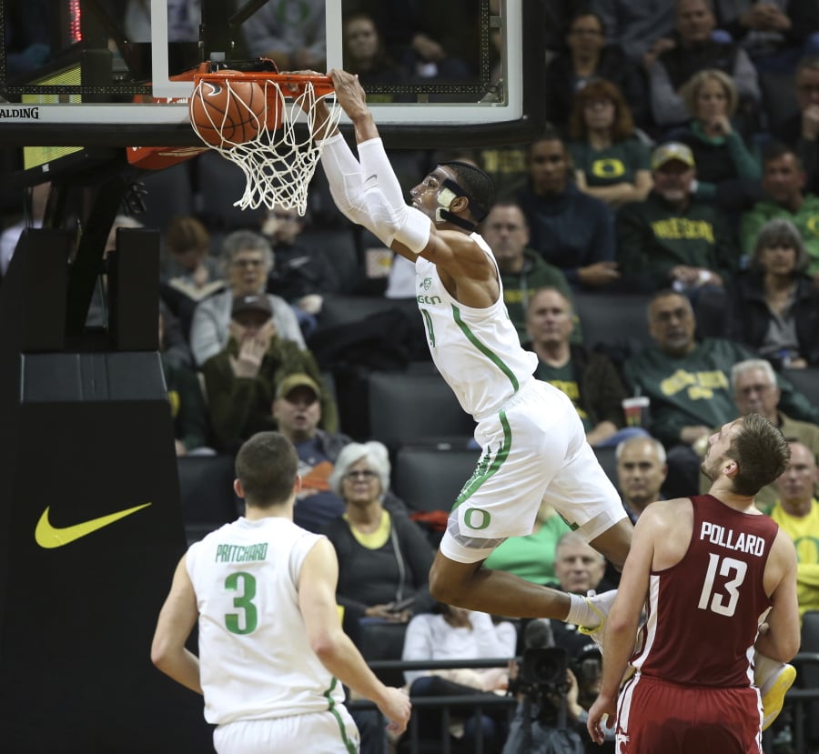Oregon’s Kenny Wooten, top, dunks over teammate Payton Pritchard, left and Washington State’s Jeff Pollard, right, during the second half of an NCAA college basketball game Sunday, Jan 27, 2019, in Eugene, Ore.