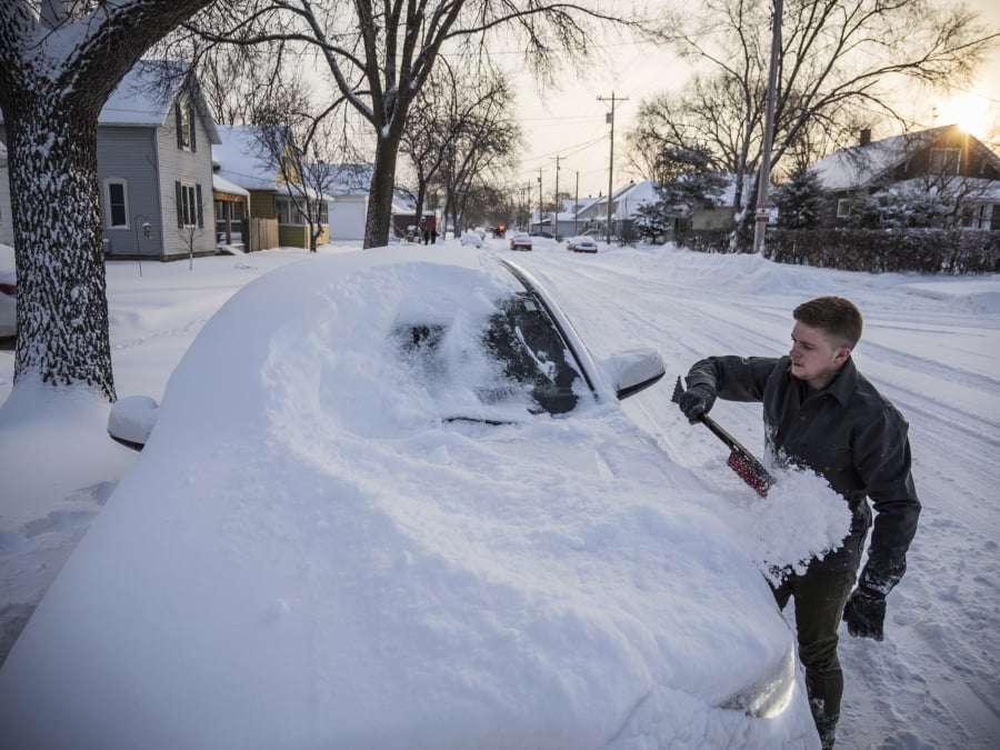 Andy Maxfield brushes snow from his truck outside his home after heavy snow overnight Monday, Jan. 28, 2019, in Rochester, Minn. Heavy snow and gusting winds created blizzard-like conditions Monday across parts of the Midwest, prompting officials to close hundreds of schools, courthouses and businesses, and ground air travel.