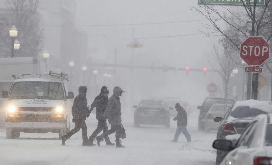 People walk through a snowstorm in downtown Jackson, Mich., on Monday. J.