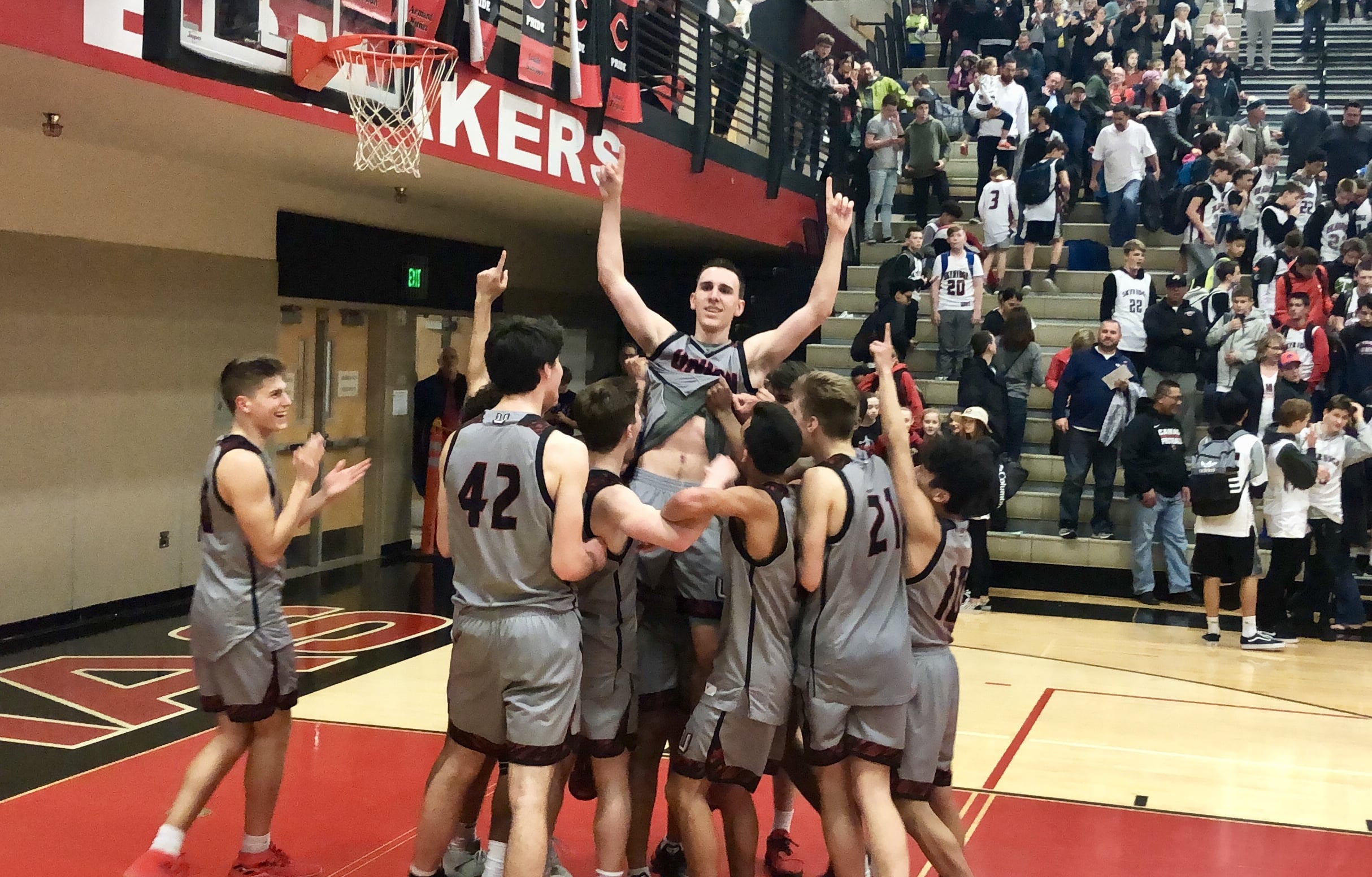 The Union boys basketball team lifts up Ethan Smith moments after an 82-68 win over Camas in which he hit a school-record eight 3-pointers on Friday night at Camas High School.