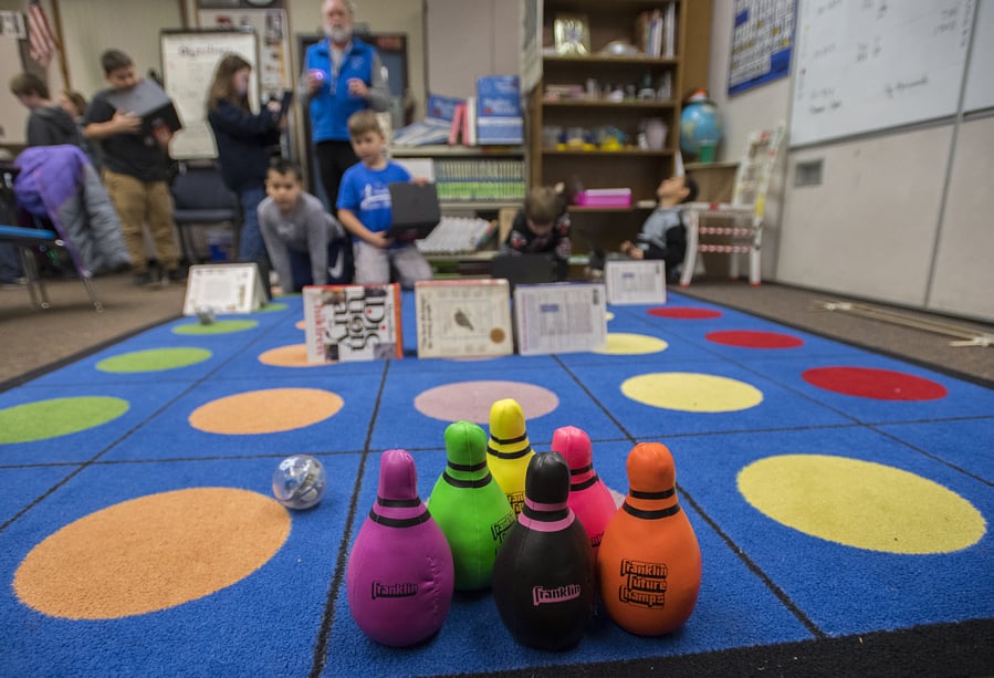Teacher Mark Sterling, blue vest, and a fourth-grader at Silver Star Elementary School watch as they maneuver a “sphero”, left, in an attempt to knock down stuffed bowling pins while controlling them from across the room. A program levy and technology levy were both passing Tuesday night.