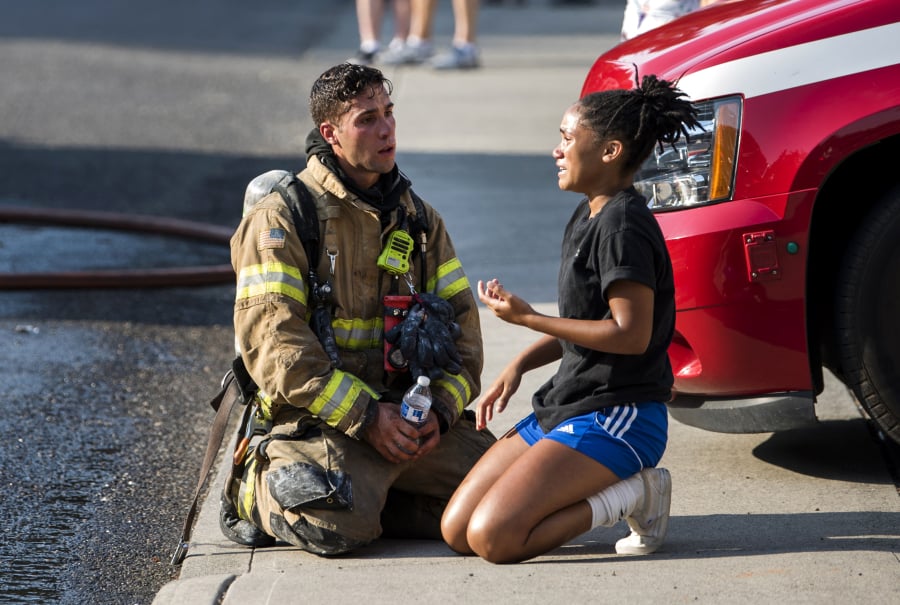 Clark County Fire District 6 firefighter Dominic Sepe comforts Olivia Calton, 15, as firefighters work to put out a fire at her home on the evening of July 30, 2018, in Vancouver. Columbian staff photographer Alisha Jucevic, who captured the moment, was recognized Friday with an Award of Excellence in the prestigious Pictures of the Year International photo contest.