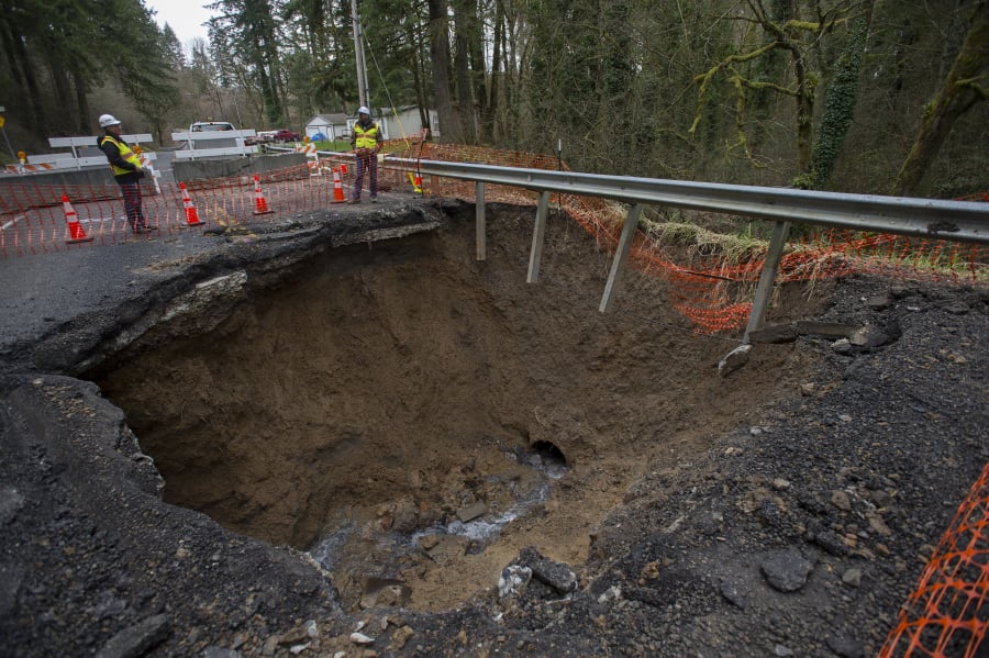 Clark County Public Works spokesman Jeff Mize, left, and bridge and culvert manager Ken Price look over a collapsed section of Northwest Pacific Highway in La Center. The road has been closed since Feb. 12 and is expected to remain closed for a few months while the county works to repair it.