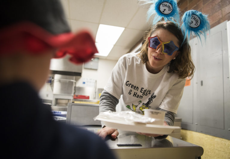 Chele Diffenbaugh, volunteer with Beaches, serves green eggs and ham to first-graders at at Martin Luther King Elementary School to celebrate the 115th birthday of Theodor Seuss Geisel in Vancouver on Wednesday, Feb. 27, 2019. Beaches Restaurant &amp; Bar owner Mark Matthias and a team of volunteers are feeding green eggs and ham Ñ inspired by the book of the same name Ñ to first-graders and their parents at elementary schools in the Vancouver and Evergreen districts, as well as other county schools throughout the week.