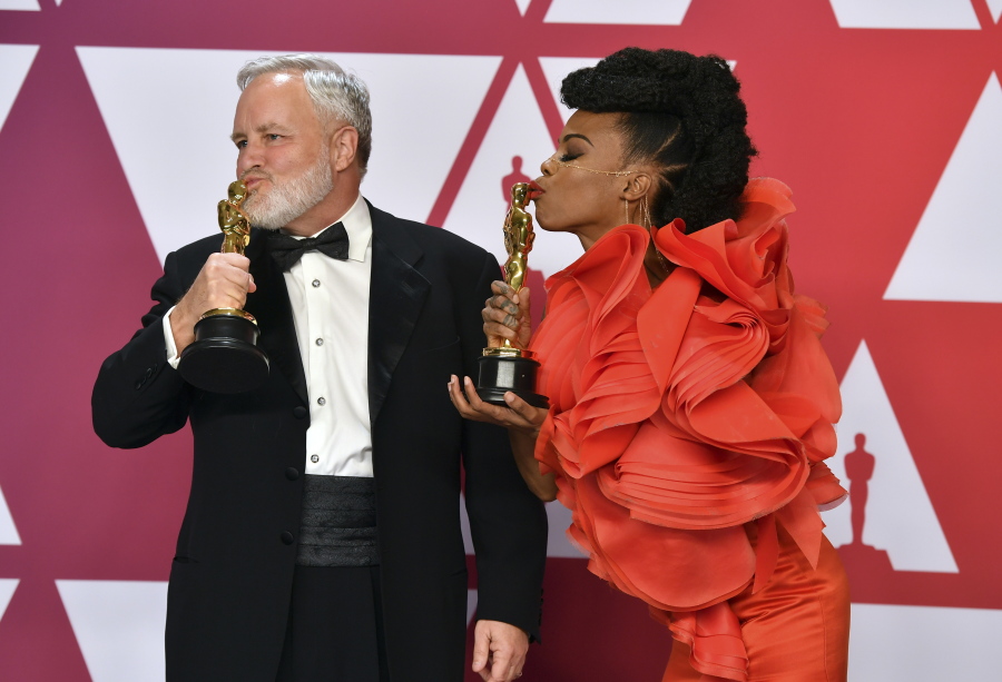 Jay Hart, left, and Hannah Beachler kiss their awards for best production design for “Black Panther” in the press room at the Oscars on Sunday, Feb. 24, 2019, at the Dolby Theatre in Los Angeles.