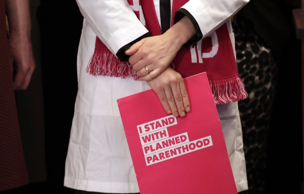 Dr. Erin Berry, Washington State Medical Director for Planned Parenthood of the Great Northwest and the Hawaiian Islands, holds a folder as she listens at a news conference announcing a lawsuit challenging the Trump administration's Title X "gag rule" Monday, Feb. 25, 2019, in Seattle. The rule issued last Friday would impact federal funding for reproductive health care and family planning services.