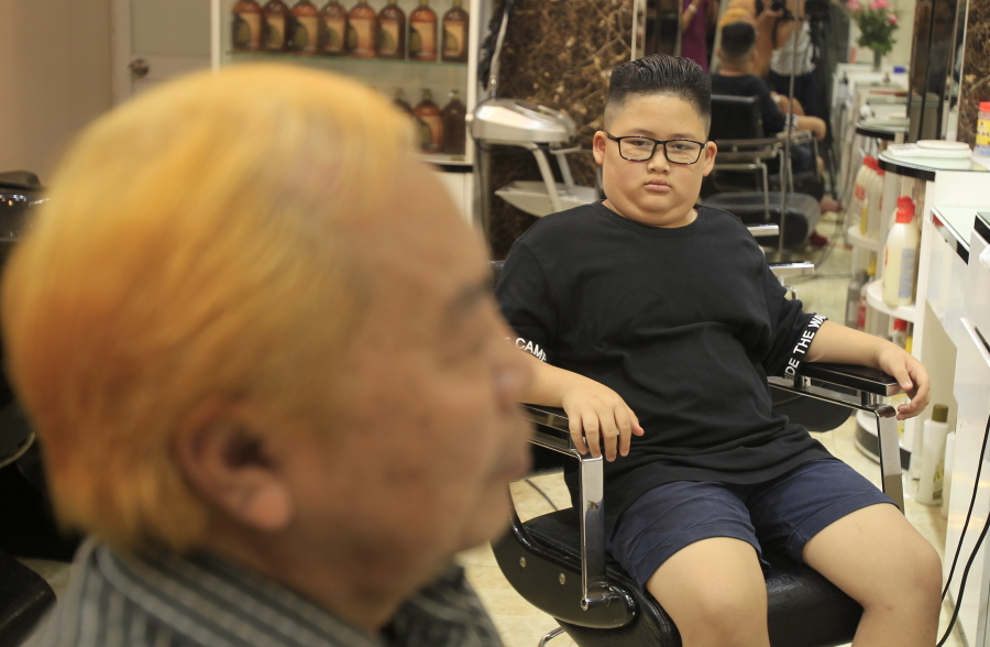 Le Phuc Hai, 66, left, and To Gia Huy, 9, sit after having Trump and Kim haircuts in Hanoi, Vietnam, on Tuesday, Feb.19, 2019. U.S.