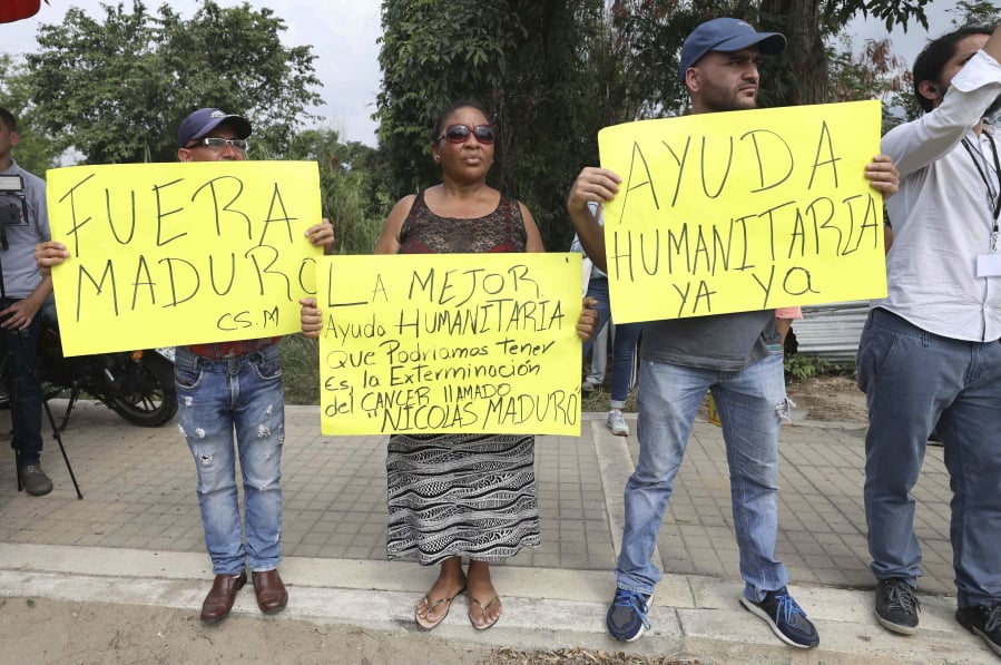 Venezuelan citizens protest against President Nicolas Maduro at the Tienditas International Bridge, near Cucuta, Colombia, on the border with Venezuela, Thursday, Feb. 7, 2019. Messages on poster in Spanish read from left to right: “Maduro get out”; “The best humanitarian aid that we could receive is the extermination of the cancer called Maduro”; and “Humanitarian help now!”.