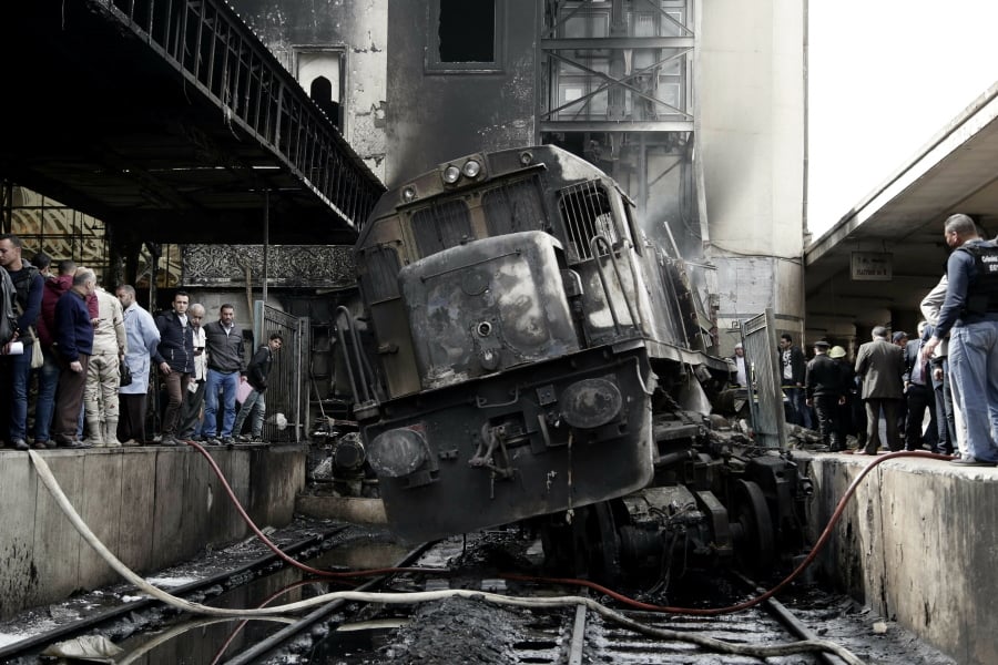People look at a damaged train inside Ramsis train station in Cairo, Egypt, Wednesday, Feb. 27, 2019. An Egyptian medical official said at least 20 people have been killed and dozens injured after a railcar rammed into a barrier inside the station causing an explosion of the fuel tank and triggering a huge blaze that engulfed that part of the station. The head of the Cairo Railroad Hospital said the death toll is expected to rise further.