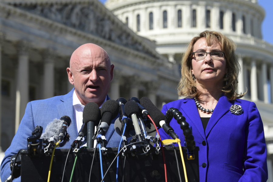 FILE- In this Oct. 2, 2017, file photo former Rep. Gabrielle Giffords, D-Ariz., right, listens as her husband Mark Kelly, left, speaks on Capitol Hill in Washington. Kelly is kicking off his U.S. Senate campaign Saturday, Feb.