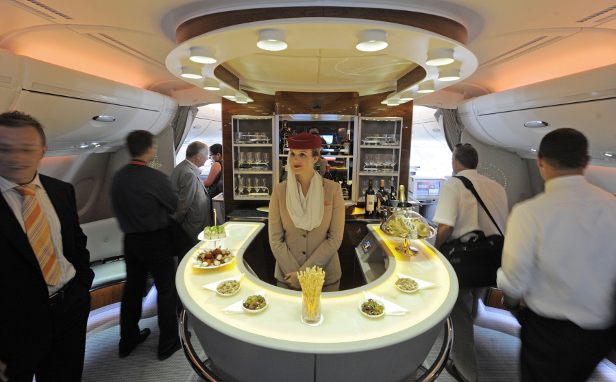 FILE- In this July 13, 2010, file photo Nadine Schumacher, center, works at the bar in the first class section on board Airbus A380 passenger plane of Emirates Airline during the International Air Show ILA at Schoenefeld airport in Berlin. European plane maker Airbus said Thursday, Feb. 14, 2019, that it will stop making its superjumbo A380 in 2021 for lack of customers, abandoning the world’s biggest passenger jet and one of the aviation industry’s most ambitious and most troubled endeavors.
