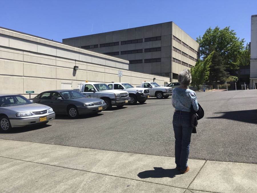 FILE - In this Wednesday, May 24, 2017 photo, Terry Carlisle looks at the Douglas County Jail in Roseburg, Ore., where she was incarcerated under what she describes as horrific conditions in 2015 for drunken driving. After being sued by a woman who was jailed under conditions she described as inhumane, officials in an Oregon county have agreed to lower the number of inmates crammed into a single cell, allow them showers twice a week and provide menstruating prisoners with hygiene products.