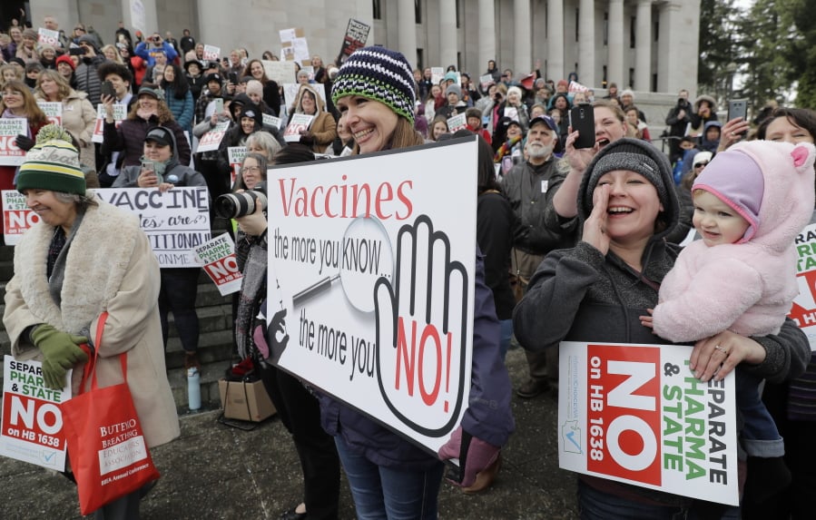 Lacey Walter of Kennewick holds a sign that reads “Vaccines, the more you know, the more you No!” on Friday, Feb. 8, at the Capitol in Olympia at a rally opposing a proposed bill that would remove the ability of parents of school-age children to claim a philosophical exemption to opt out of the combined measles, mumps and rubella vaccine. (Ted S.