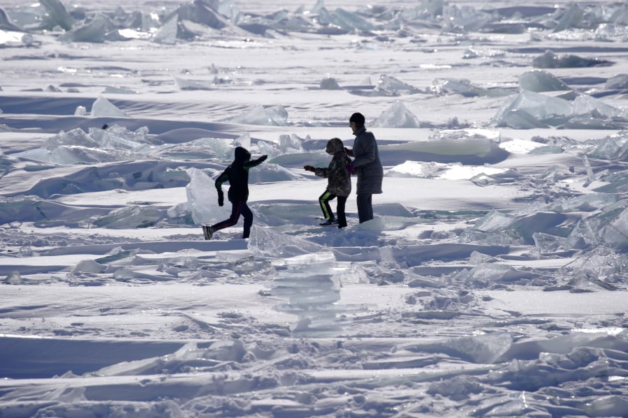In this Friday, Feb. 22, 2019, photo, people play on the Ice on Lake Superior, starting to pack in along the shore near Duluth, Minn., and attracting explorers and ice fishermen out on to the lake. Access to the mainland ice caves remain CLOSED. Ice continues to move around quite a bit. Over the last few days, open water has been visible from Meyers Beach as well as near Eagle Island. This ice is typically poor quality ice, which reacts poorly to movement due to weak bonding along the fractures.