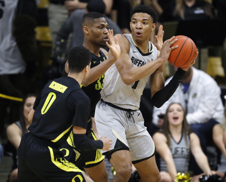 Colorado guard Tyler Bey, right, looks to pass the ball as Oregon forward Francis Okoro, back left, and guard Will Richardson defend in the first half of an NCAA basketball game Saturday, Feb. 2, 2019, in Boulder, Colo.