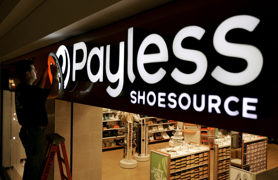 FILE- In this May 18, 2006, file photo a worker puts the finishing touches on a sign unveiling the company’s new look at a Payless Shoesource store at a mall in Independence, Mo. Payless ShoeSource has filed for Chapter 11 bankruptcy protection and is shuttering its remaining stores in North America. The filing on Monday, Feb. 18, 2019, came a day after the shoe chain began holding going-out-of-business sales at its North American stores.