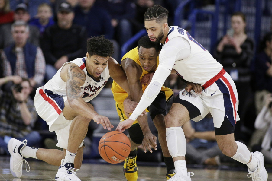 Gonzaga forward Brandon Clarke, left, guard Josh Perkins, right, and San Francisco guard Jamaree Bouyea go after the ball during the first half of an NCAA college basketball game in Spokane, Wash., Thursday, Feb. 7, 2019.