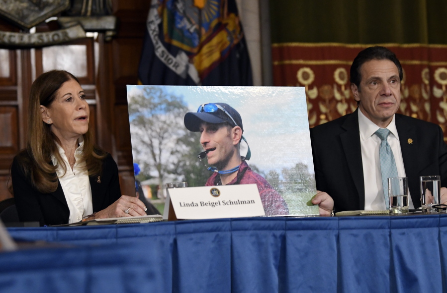 Linda Beigel Schulman, left, holds a photograph of her son, Scott Beigel, who was killed in the shooting at Marjory Stoneman Douglas High School in Parkland, Fla., while speaking with New York Gov. Andrew Cuomo and gun safety advocates Jan. 29 at the state Capitol in Albany, N.Y.