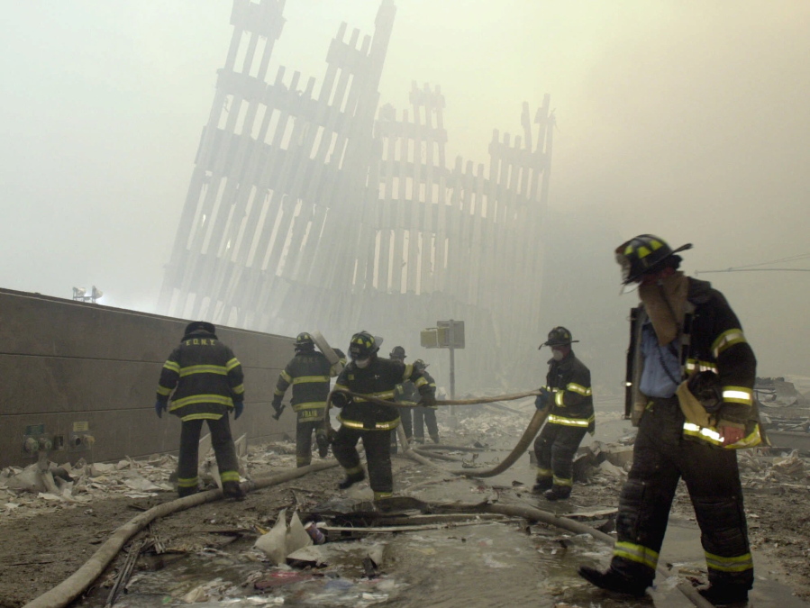 FILE - In this Sept. 11, 2001 file photo, with the skeleton of the World Trade Center twin towers in the background, New York City firefighters work amid debris on Cortlandt St. after the terrorist attacks. On Friday, Feb. 15, 2019, Rupa Bhattacharyya, the September 11th Victim Compensation Fund special master, announced that the compensation fund for victims of the Sept. 11, 2001 terror attacks will cut future payments by 50 to 70 percent because the fund is running out of money.
