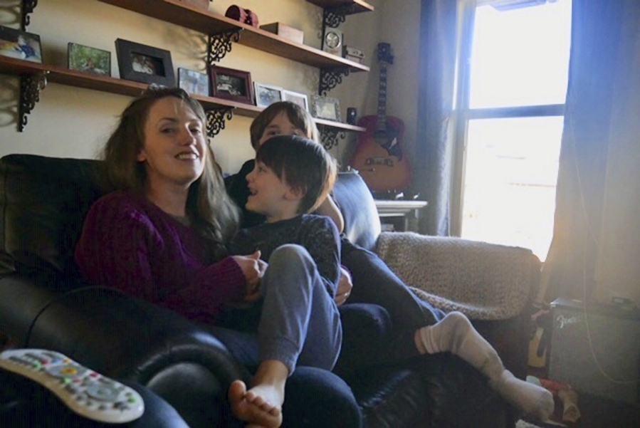 In this 2019 photo provided by Americans United for Separation of Church and State, Aimee Maddonna smiles while sitting with her children at her home in Simpsonville, S.C. The South Carolina mother has sued both the state and federal government, saying she’s a victim of religious discrimination on the part of a federally funded foster-care agency that turned her down because of her Catholic faith. Maddonna says the agency in 2014 initially encouraged her to become a foster parent but cut off ties once realizing that she is Catholic and not a “born-again” Christian, as the agency’s internal rules require.